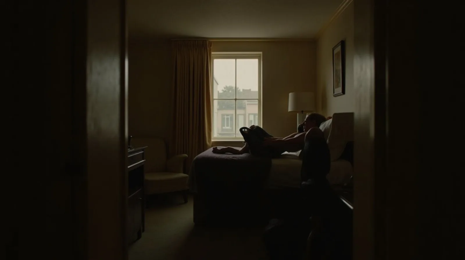 A neat hotel room with luggage on a rack and curtains being drawn, seen from the doorway