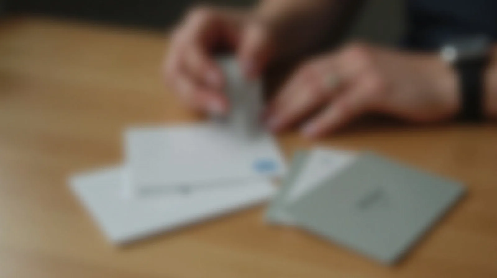 A close-up of a hand sorting a stack of store loyalty and rewards cards on a table