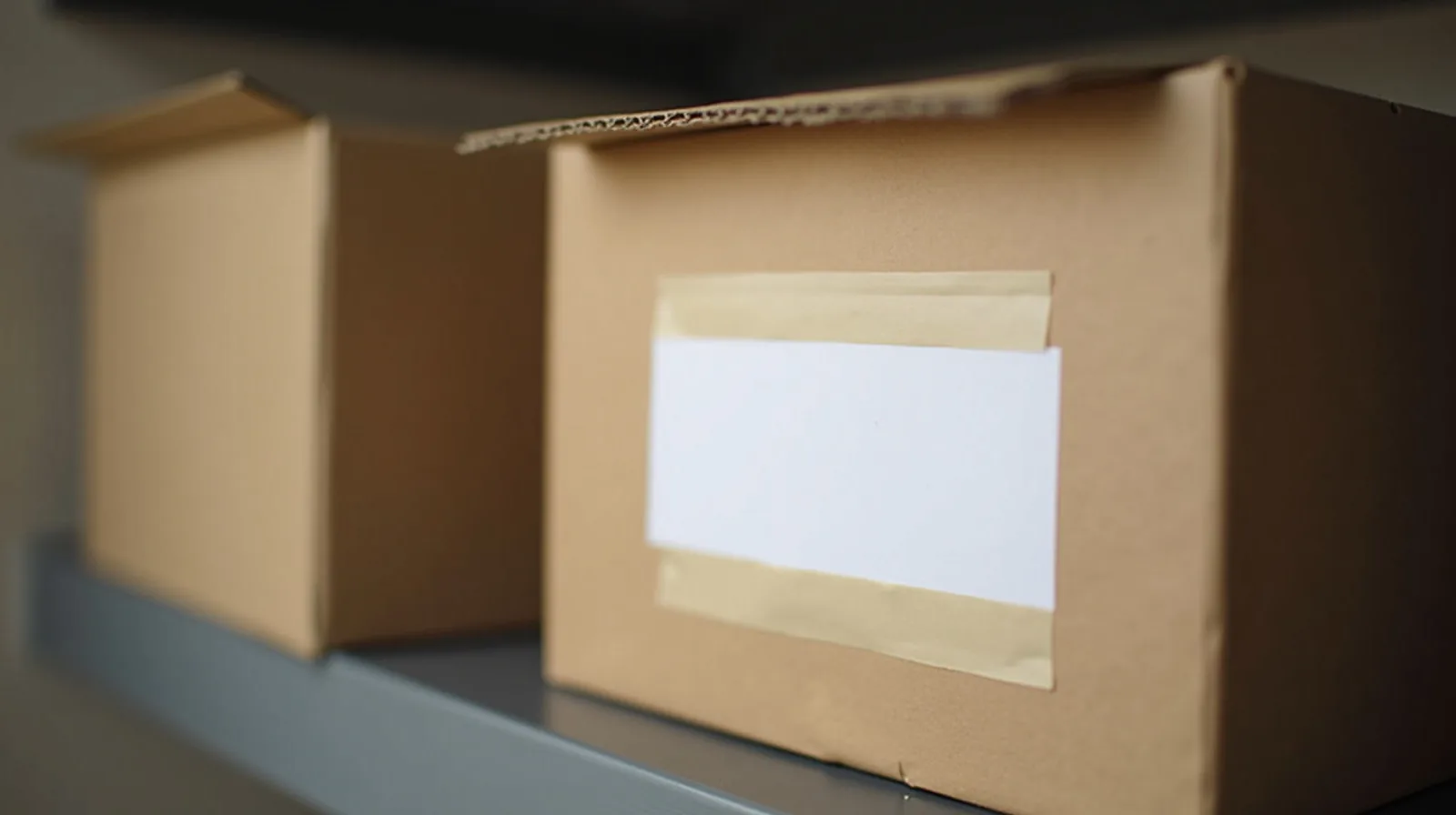 A close-up of a taped cardboard box with a blank date label on a garage shelf
